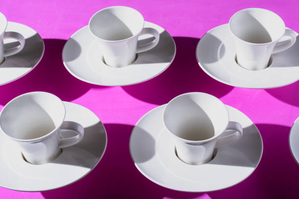 istock Pattern of coffee cups from a top view casting a hard shadow with the silhouette of another cup. Pink background. 1394802144
