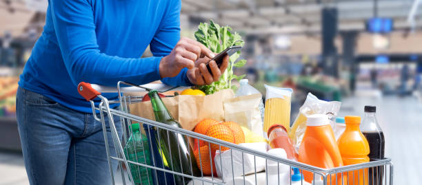 istock Man doing grocery shopping and using his smartphone 1394803494