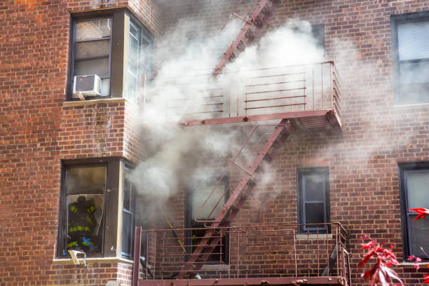 An old apartment is on fire with smoke coming out from the window.