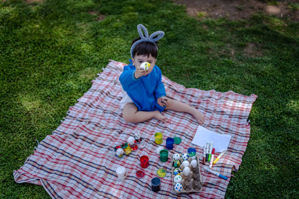 Baby boy coloring Easter eggs in the garden