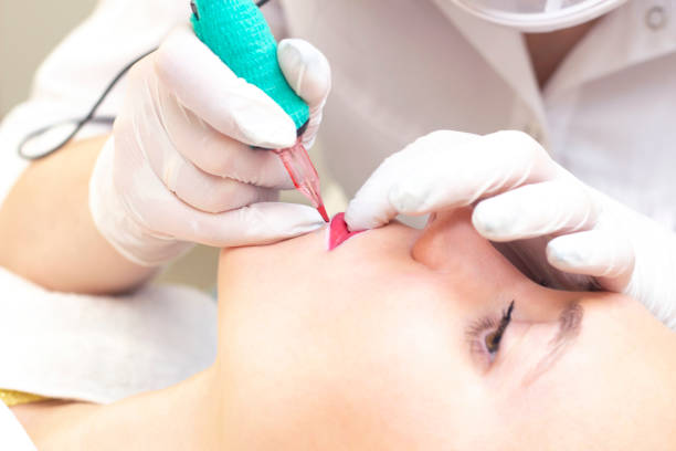 istock Young woman having permanent makeup on her lips at the beauticians salon. Permanent Makeup (Tattoo) 1394806738