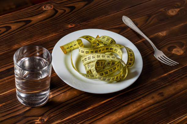 diet concept empty plate with measuring tape fork and glass with watter healthy food weight
