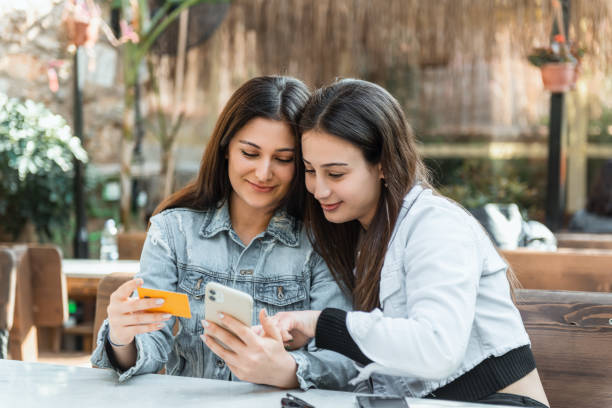 Young two women in a cafe shopping online with credit card stock photo