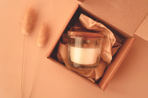 A gift box for a special occasion wrapped in pink paper and placed on a table near a gel candle.