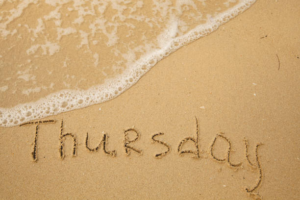 istock Thursday - handwritten on the light beach sand with a soft wave lapping. 1394814498