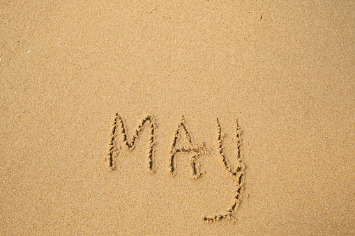 May - handwritten on the soft beach sand.