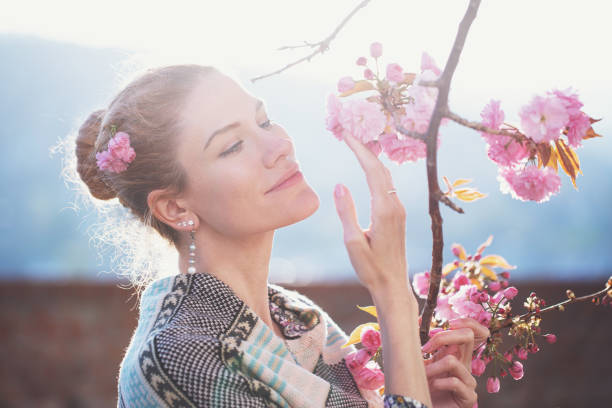 White woman in sunlight holding cherry tree blossom during springtime, femininity
