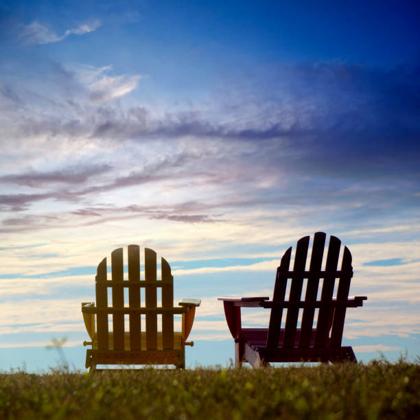 widok z poziomu powierzchni dwóch pustych drewnianych krzeseł zewnętrznych nad dramatycznym niebem na zielonym krajobrazie - deck chair summer grass outdoor chair zdjęcia i obrazy z banku zdjęć