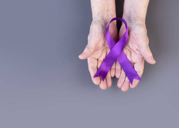 노인 여성의 손은 회색 배경에 보라색 리본을 들고 있습니다. 알츠하이머 인식 개념. - alzheimers disease 뉴스 사진 이미지