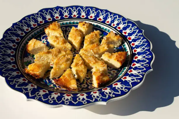 Photo of Basousa, a traditional Middle Eastern dessert. Adapted to a low-carb ketogenic diet, the cake is made with almond and coconut flour, a sweetener, and garnished with almond flakes.