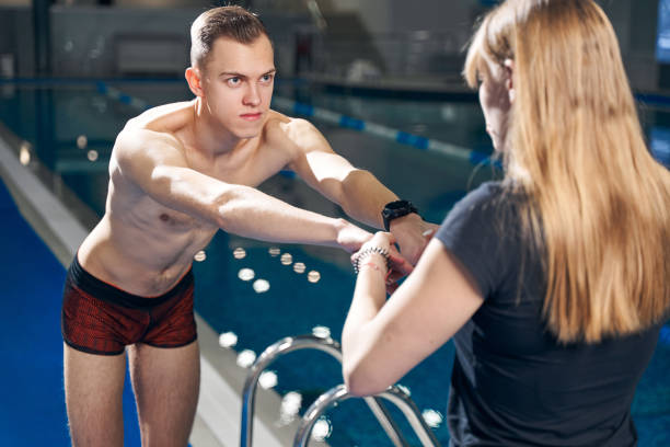 istock Athletic woman pull slim guy hands toward herself before training in the pool 1394826892