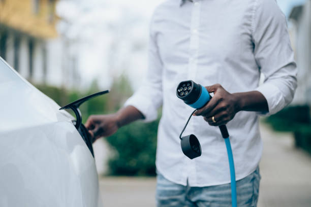 man charging electric car - elektrikli araba lar stok fotoğraflar ve resimler