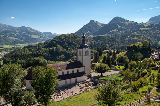 Old church with mountains in the background in summer in Gruyeres, Switzerland.