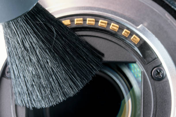 A cleaning camera lens with soft brush, close up view.