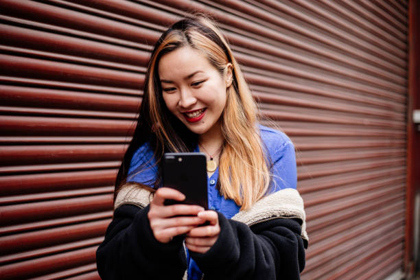 istock Young Asian Woman using phone at street 1394829379