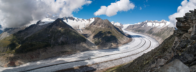 A long Aletschgletscher glacier that stretches into a bend through a deep narrow valley between high mountains (Switzerland)