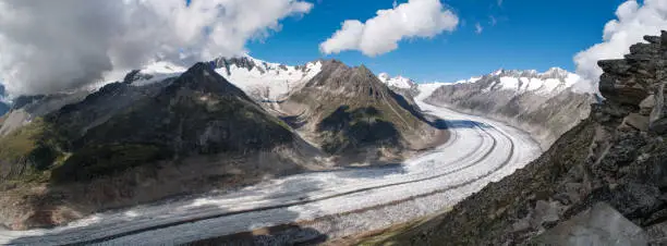 A long Aletschgletscher glacier that stretches into a bend through a deep narrow valley between high mountains (Switzerland)