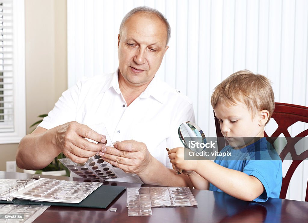 Grand-père et son petit-fils regardant collection de pièces de monnaie. - Photo de Adulte libre de droits