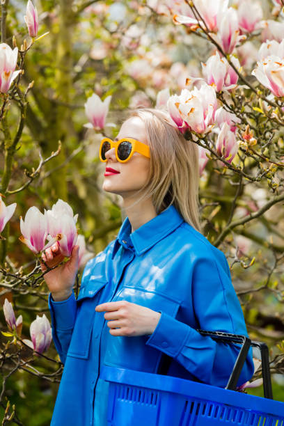 blonde frau mit korb neben magnolienbaum im frühling - magnolia blossom flower head single flower stock-fotos und bilder