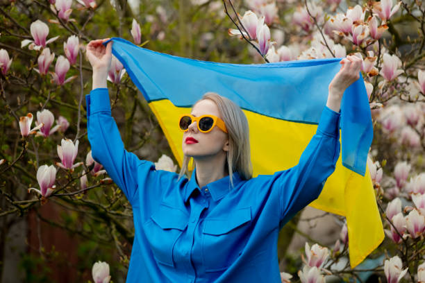 frau mit sonnenbrille und blauem hemd mit ukrainischer flagge in der nähe des magnolienbaums - magnolia blossom flower head single flower stock-fotos und bilder