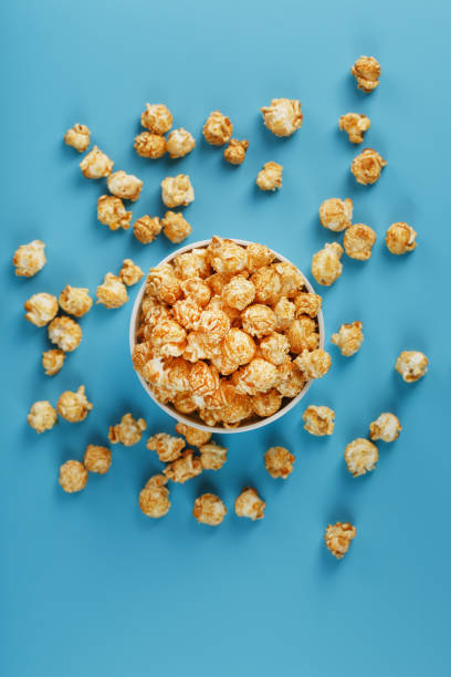 istock Caramel popcorn in a white glass cup with scissors on a blue background 1394834217