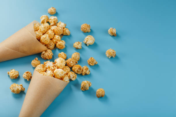 istock Caramel popcorn in a paper envelope on a blue background. 1394835268
