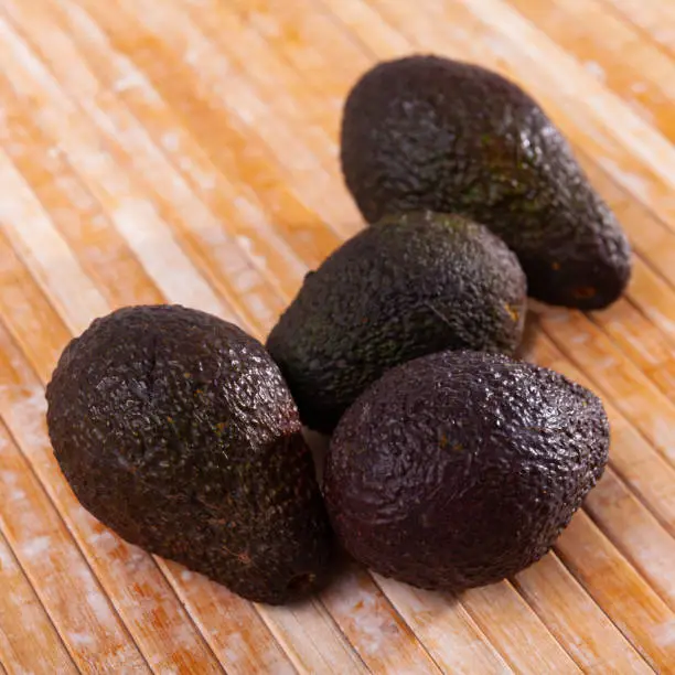 Photo of Pile of ripe whole Hass avocados on wooden background