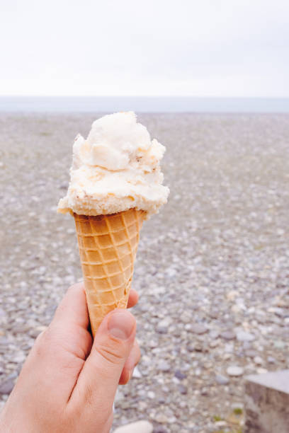 istock ice cream in hand on a beach background 1394839154