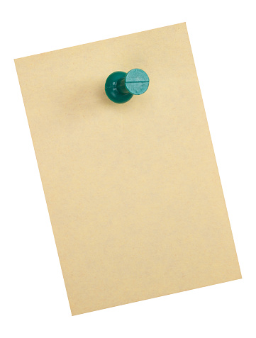 Green thumbtack on yellow note paper on white background.
