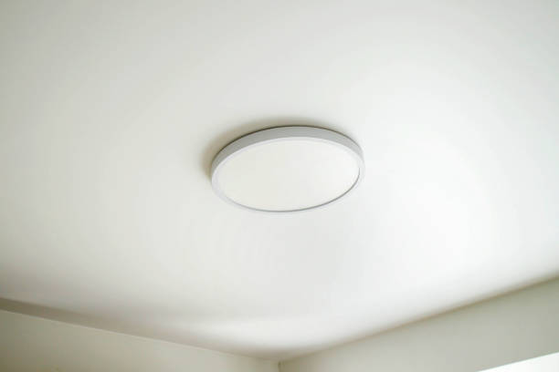 Round, minimalist, simple lamp on a white ceiling. A lamp that does not attract attention.
