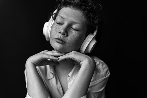 Black and white portrait of a beautiful woman with freckles listening to music