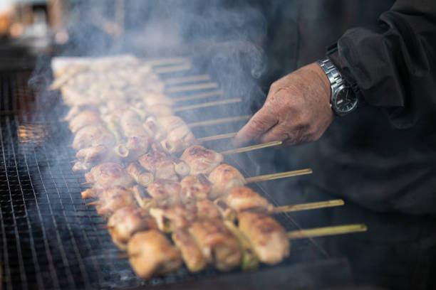 cooking yakitori meat on a skewer over barbecue grill - yakitori stok fotoğraflar ve resimler