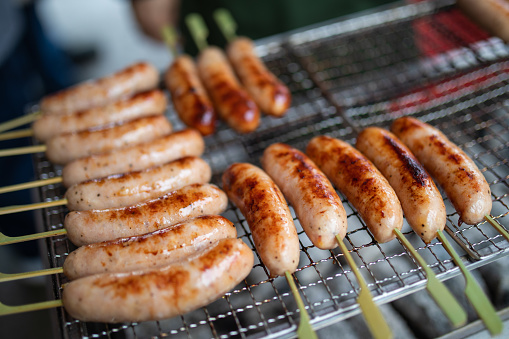 Sausages grilling at a street food stall at a Japanese festival.