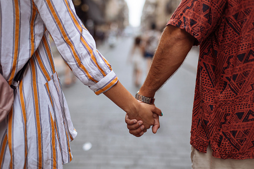 Rear view shot of an unrecognizable young couple walking through a city street while holding hands