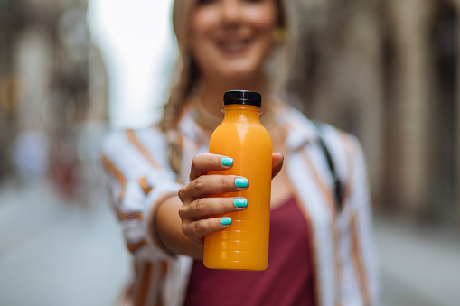 Blurred shot of a young blond woman holding a bottle of fresh juice