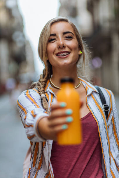 Portrait shot of a young blond woman holding a bottle of fresh juice