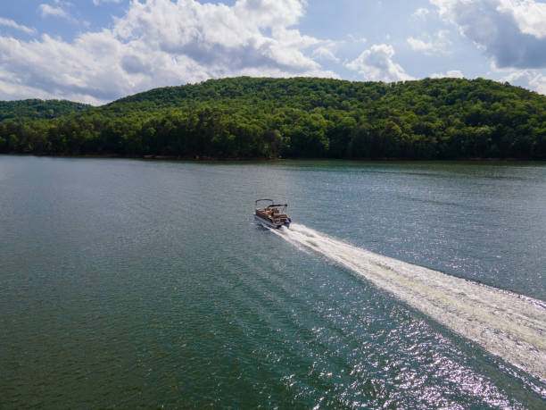 Pontoon Boat at Full Throttle On Lake Pontoon boat traveling at full throttle across open lake. Party barge on Lake Altoona during the summer. pontoon boat stock pictures, royalty-free photos & images