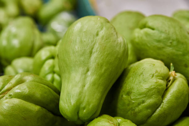 Green chayotes placed on a shelf for sale inside a market