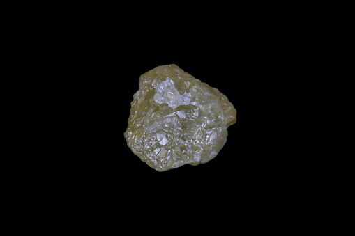 Raw, uncut yellow diamond. 5.7mm diameter, weight 1.9 carats. On Black background.
