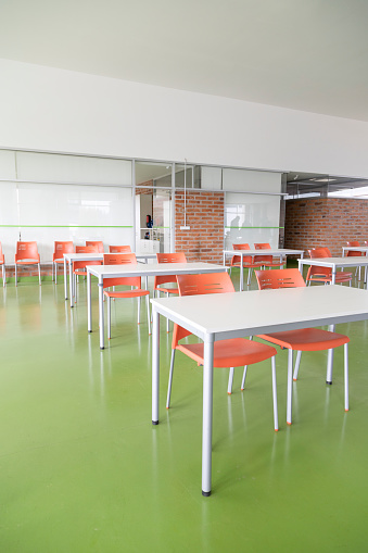 interior decoration of a classroom with colorful desks, seats and floor, modern furniture, spacious place without people, objects