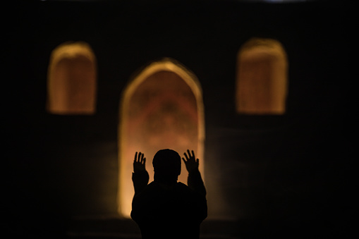 Silhouette of mosque building on toned foggy background. Ramadan Kareem background. Realistic mosque miniature with prayer silhouette. Selective focus