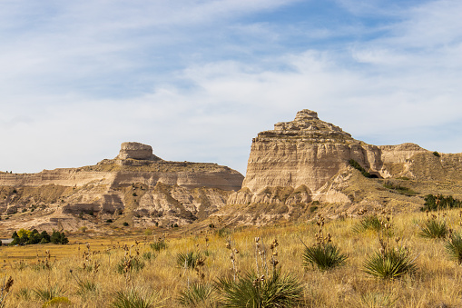 Dwarfed by the eroded formations, a distant hiker walks the badland layers of hardened volcanic ash, clay and sandstone in Toadstool Geologic Park in the Oglala National Grassland of Nebraska.