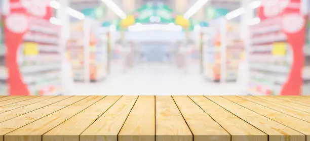 Photo of Empty wood table top with supermarket grocery store aisle and shelves blurred background