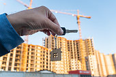 key in hands against the background of construction of a modern building