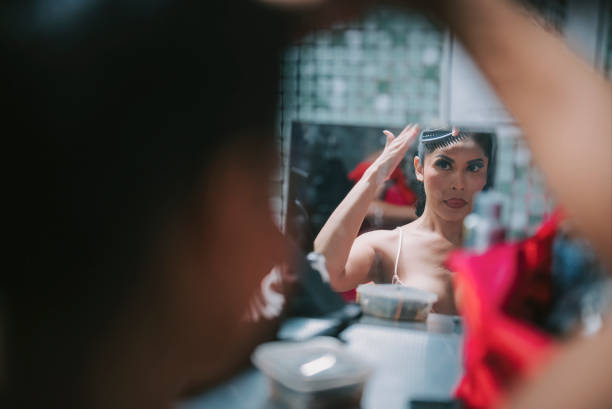 Asian Chinese drag queen combing wig getting ready for performance at pub in dressing room Asian Chinese drag queen combing wig getting ready for performance at pub in dressing room drag queen stock pictures, royalty-free photos & images