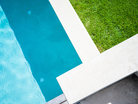 Dynamic and modern pool edge design, Birdseye view, copy space. Bold blue and green colours, intercepted with white marble.