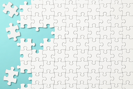 Overhead shot of white blank jigsaw puzzle on light blue background.