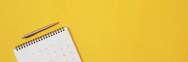 istock close up top view calendar schedule to make appointment meeting or manage timetable each day lay on yellow background for planning work and travel concept. 1394882739