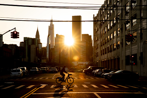 Bicyclist riding past the city sunset in New York City.