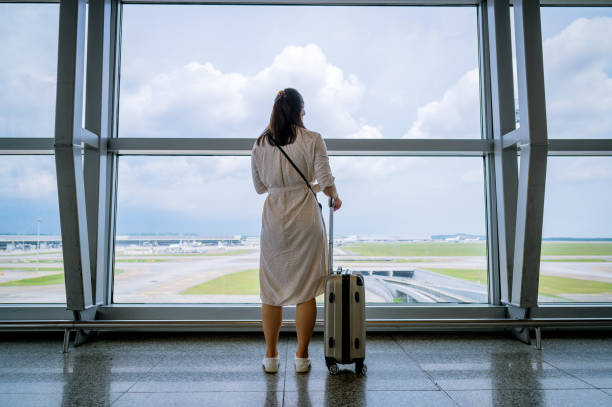 istock Young Asian woman pulling suitcase in airport terminal 1394888705